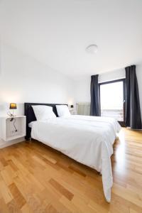 Schlafzimmer mit einem großen weißen Bett und Holzboden in der Unterkunft Großzügiges Ferienhaus in ruhiger Lage in Würzburg