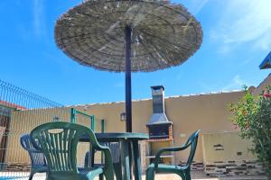 ein Tisch mit Stühlen und einem Sonnenschirm auf einer Terrasse in der Unterkunft Bungalow Curro Pareja 97 in Conil de la Frontera