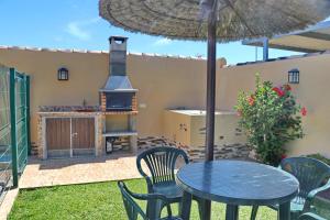 eine Terrasse mit einem Tisch und Stühlen sowie einem Backofen im Freien in der Unterkunft Bungalow Curro Pareja 97 in Conil de la Frontera