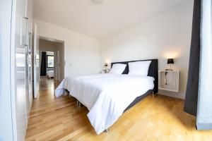 Schlafzimmer mit einem großen weißen Bett und Holzböden in der Unterkunft Großzügiges Ferienhaus in ruhiger Lage in Würzburg