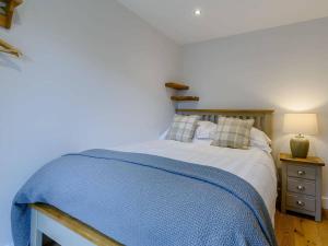 a bedroom with a bed with a blue blanket at Rinstone Lodge, Thornton-Le-Dale. Moors cottage with hot tub in Thornton Dale