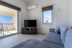 a living room with a blue couch and a tv at Breakaway Apartment in Cres