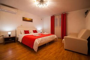 a bedroom with a bed with a red blanket and a chair at Holiday Home Baki in Bol
