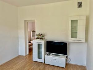 uma sala de estar com televisão e uma parede branca em Apartmán Na Polabí em Mělník