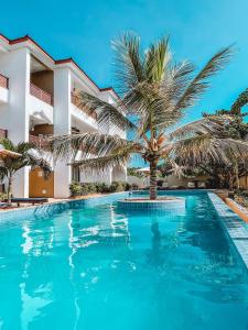 une piscine avec un palmier en face d'un bâtiment dans l'établissement Zanzibar Star Resort, à Nungwi