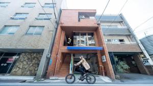 uma pessoa numa bicicleta em frente a um edifício em HOSTEL PAQ tokushima / Vacation STAY 35580 em Tokushima