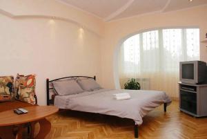 Schlafzimmer mit einem Bett, einem TV und einem Tisch in der Unterkunft Apartment near train station and close to city center in Kiew