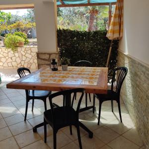 una mesa de madera y sillas en un patio en Baglio Cracchiolo da Tuzzo - Casa Bouganville en San Vito lo Capo
