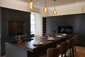 a kitchen with black cabinets and a island with chairs at Lochieheads House in Cupar