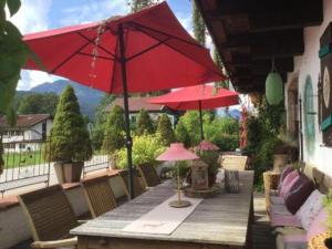 een houten tafel met rode parasols op een patio bij Pension Louise in Reit im Winkl