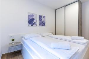 two beds in a room with white walls at Apartment Blue Monstéra in Cres