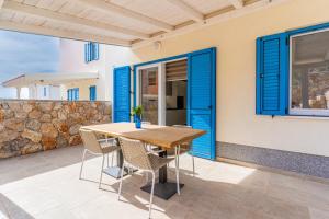 a table and chairs on a patio with blue shutters at Apartment Blue Monstéra in Cres