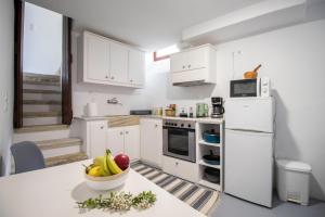 a kitchen with white appliances and a bowl of fruit on a counter at Platsa's House in Apérathos