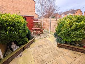 un jardín con una mesa y algunos arbustos y una valla en 2 bedroom home in quiet location close to Chester en Hough Green