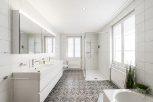 ein weißes Bad mit 2 Waschbecken und einer Dusche in der Unterkunft Verena's Boutique Villa au lac in Sachseln