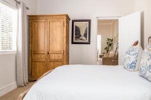 una camera da letto con un letto e un armadio in legno di Petit Ermitage a Franschhoek Altre 19 foto
