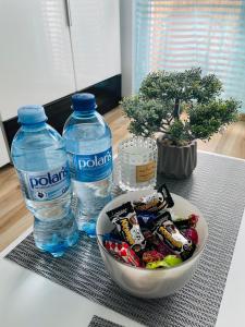 a bowl of candy and two bottles of water on a table at Elli apartament in Gdynia