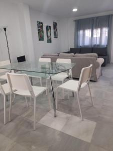 a glass table and white chairs in a living room at CASA INDEPENDIENTE EN NERVION JUNTO A PARADA DEL METRO in Seville