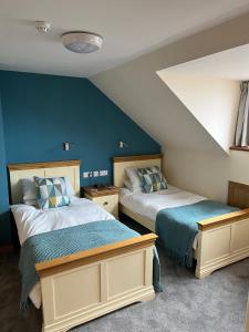 two beds in a room with blue walls at Karrawa Guest House in Kirkwall
