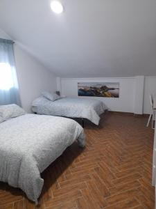 a bedroom with three beds and a wooden floor at CASA INDEPENDIENTE EN NERVION JUNTO A PARADA DEL METRO in Seville