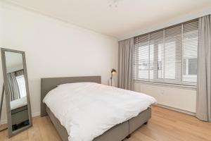 a white bedroom with a large bed and a mirror at Between the theaters of Antwerp in Antwerp
