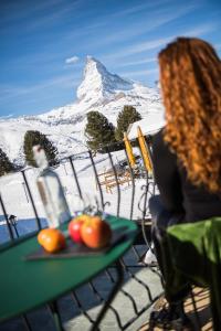a woman sitting at a table with a tray of fruit at Riffelalp Resort 2222m in Zermatt