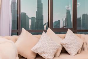 a white couch with pillows in front of a window at Elite Royal Apartment - Panoramic Full Burj Khalifa, Fountain & Skyline view - Infinite in Dubai
