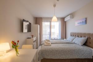 Sunny Dream Apartments في صوفيا: غرفة نوم بيضاء مع سرير ومكتب أبيض