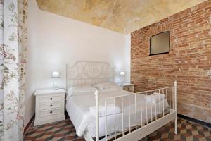 a bedroom with a white bed and a brick wall at Bilocale Merlino in Finale Ligure