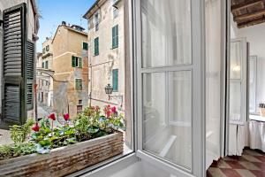 an apartment balcony with a window and flowers at Bilocale Merlino in Finale Ligure