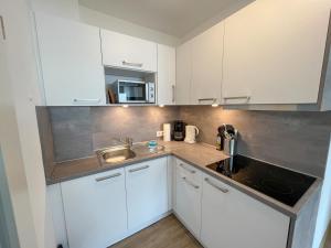 a kitchen with white cabinets and a sink at Appartementhaus Nige Ooge Ferienwohnung Nr. 1 in Cuxhaven