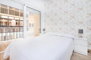 1 dormitorio con cama blanca y ventana grande en BHost - Soho, en Málaga