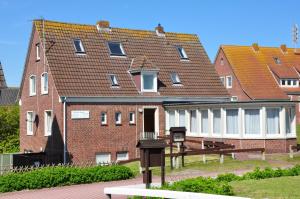 ein großes Backsteingebäude mit einer Bank davor in der Unterkunft Seevilla Wietjes Whg 5 in Baltrum