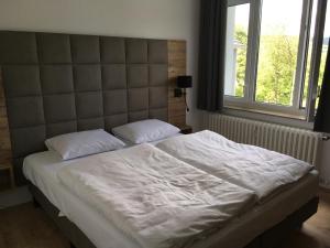 ein Bett mit weißer Bettwäsche und Kissen in einem Schlafzimmer in der Unterkunft Alte Schule Züschen-Winterberg in Winterberg
