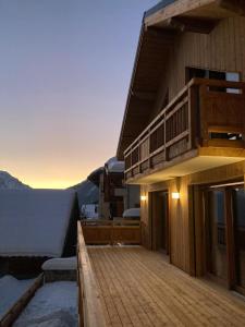 a building with a deck with a view of the mountains at Le refuge des Sens Chalet Harmonie in Vaujany