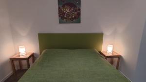 a bedroom with a green bed and two lamps on tables at B&B Dafne Marsala Centro in Marsala