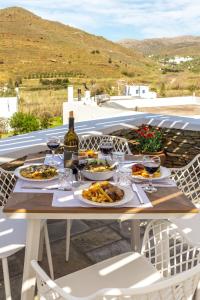 uma mesa com pratos de comida e copos de vinho em Ursa Major Suites em Tinos