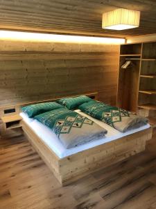 a bed in a log cabin with two pillows at Haus Landschisott in Tschagguns