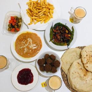 una mesa blanca con platos de comida y papas fritas en Taharka Nubian House, en Asuán