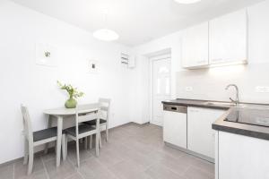 a kitchen with white cabinets and a table and chairs at Apartment Morris in Veli Lošinj