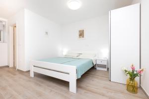 a white bedroom with a bed and a vase of flowers at Apartment Morris in Veli Lošinj