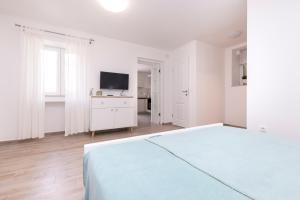 ein weißes Schlafzimmer mit einem Bett und einem TV in der Unterkunft Apartment Morris in Veli Lošinj