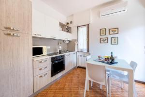 - une cuisine avec des placards blancs, une table et des chaises dans l'établissement Appartamento Emma, à Gardone Riviera