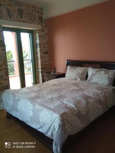 1 dormitorio con 1 cama grande y ventana en Villa Sklithro in the heart of the forest with magnificent view of the sea just 10 minutes from it, en AgiaKampos