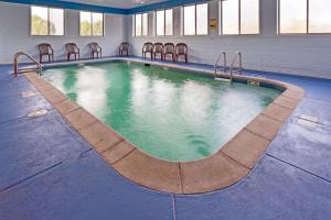 a swimming pool in a building with chairs around it at Super 8 by Wyndham DeKalb IL in DeKalb