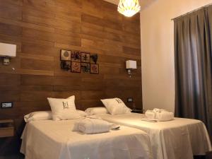 2 camas con ropa de cama blanca en una habitación en LA ATALAYA, en Los Yébenes