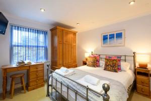 a bedroom with a bed and a desk and a window at Beachcombers Apartments in Newquay