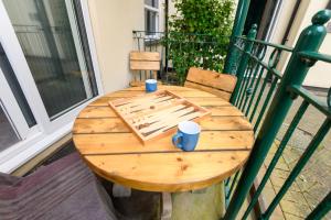a wooden table on a balcony with cups on it at Beachcombers Apartments in Newquay