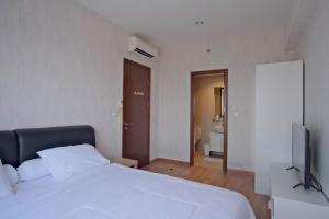 a bedroom with a white bed and a flat screen tv at 1BR Apartment Serpong Mtown Signature seberang SMS Mall in Pumpangsineng