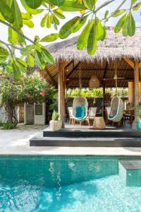 a resort with a swimming pool and chairs and a thatch roof at Tigerlillys Boutique Hotel in Nusa Lembongan